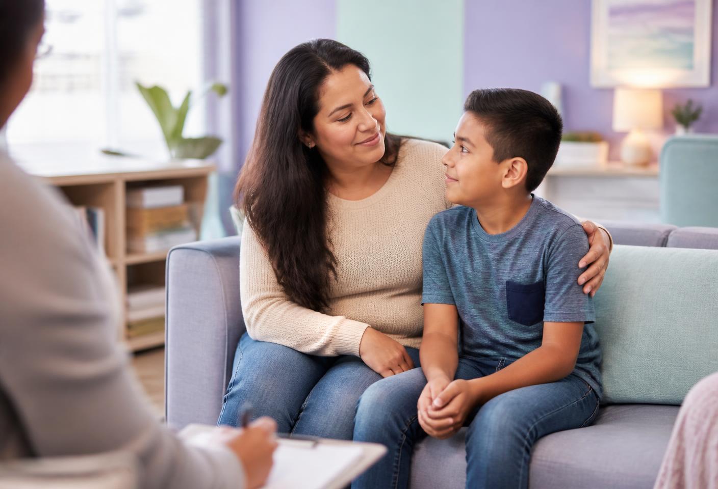 A Latino mother and her son speaking with a counselor in a calm, welcoming room.